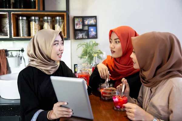Perempuan hijab dan teman-teman menggunakan tablet digital sambil menunggu melanggar puasa mereka — Stok Foto