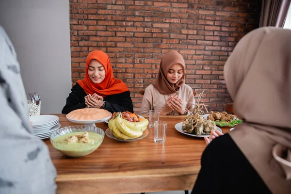 Хиджаб женщины молятся вместе перед едой — стоковое фото