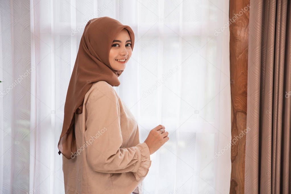 Beautiful woman veiled standing near curtain looking back and smiling