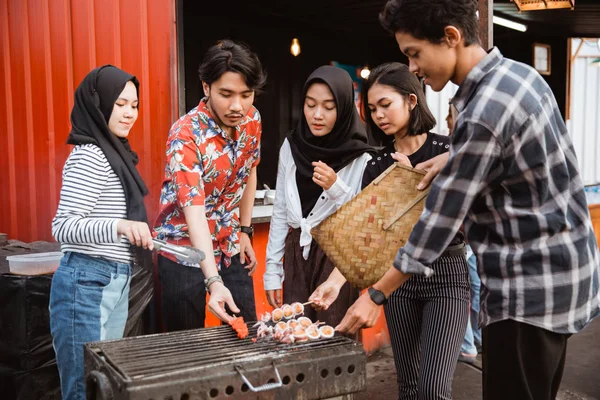 Grupo de amigos grelhar comida com um espeto — Fotografia de Stock