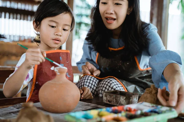 Мать и дочь рисуют керамический горшок — стоковое фото