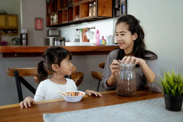 Pequeña chica asiática comiendo cereal para el desayuno con mamá —  Fotos de Stock