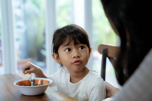 Little asian girl eating cereal for breakfast with mom — Stock Photo, Image