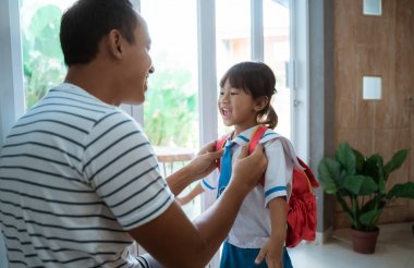 okul üniforması giyen anaokulu öğrencisi babası tarafından yardım