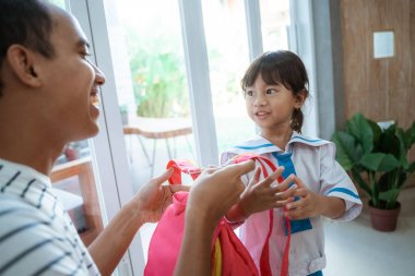 baba kızına sırt çantası koymak için yardım