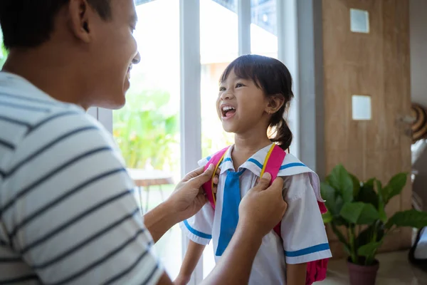 父亲帮助她的学步的孩子准备在早上的学校 — 图库照片