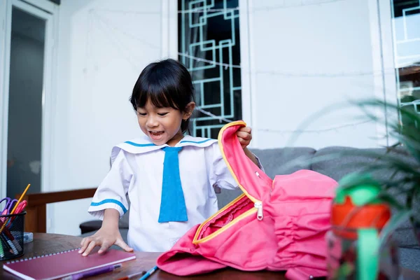 Criança vestindo uniforme escolar colocar algum livro em sua mochila — Fotografia de Stock