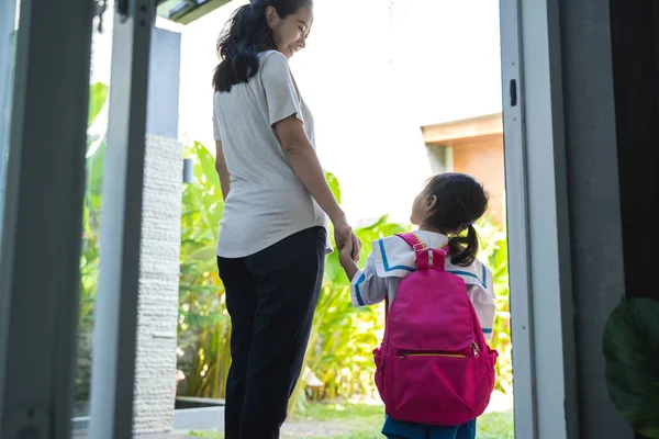 Madre cogida de la mano de la pequeña hija con mochila —  Fotos de Stock