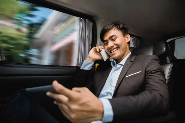 Businessman calling by phone and using tablet in the car — Stock Photo, Image