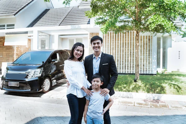 Parent avec enfant devant leur voiture souriant — Photo