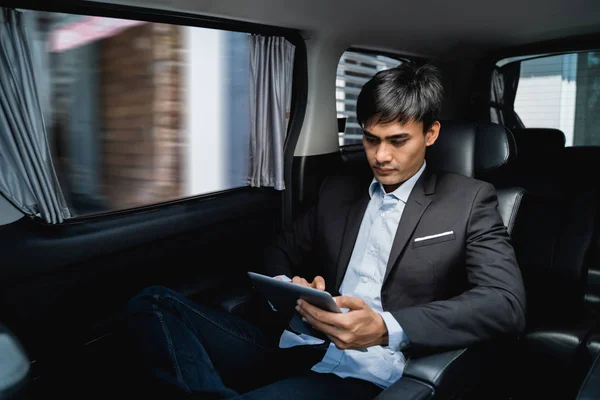 Executive using tablet while in the car on his way to the office — Stock Photo, Image
