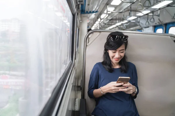 woman enjoying train trip or tram with her mobile phone