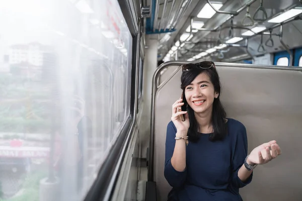 Женщина наслаждается поездкой на поезде или трамвае с ее мобильного телефона — стоковое фото