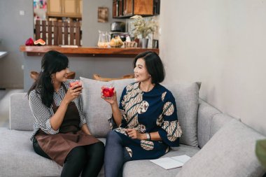 Oturma odasında otururken iki Asyalı kadın sohbet