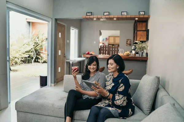 Daughter give a glass of cocktail to her mother at living room — Stock Photo, Image