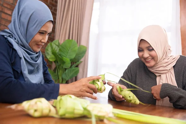 Las mujeres hacen comida tradicional ketupat para las celebraciones del Eid en casa —  Fotos de Stock