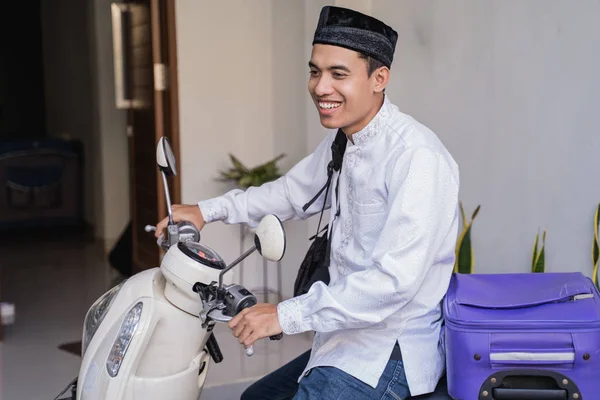 Muslim man ride motorcycle for idul fitri balik kampung mudik carrying suitcase — Stock Photo, Image