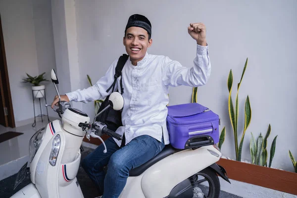 Muslim man ride motorcycle for idul fitri balik kampung mudik carrying suitcase — Stock Photo, Image