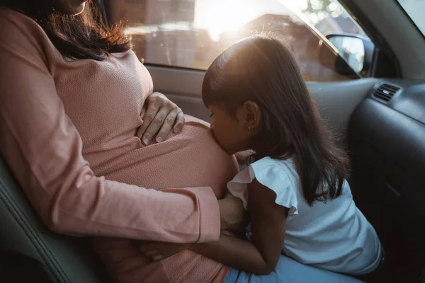 Mutter auf der Reise sitzend mit dem Kuss ihrer Tochter auf den Bauch — Stockfoto