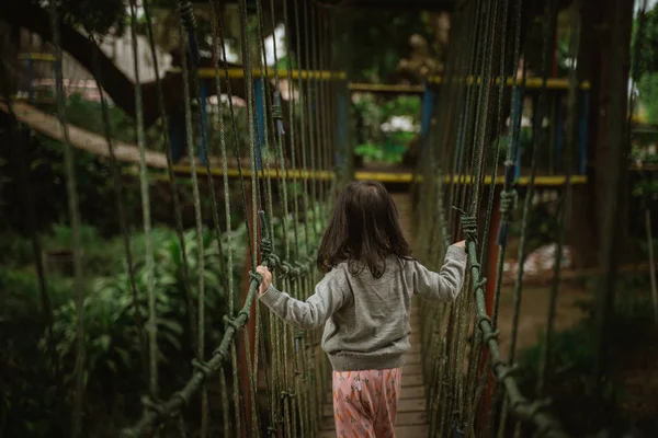 Kid spelen op buiten speeltuin in de natuur Crossing hangende brug — Stockfoto