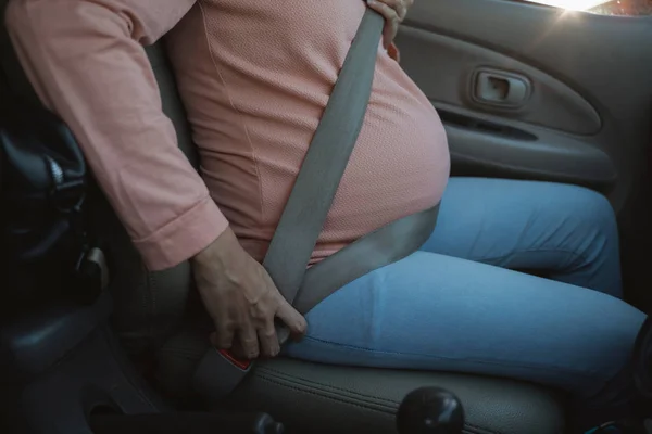 妊娠中の女性は車の上に座っている間、彼女のシートベルトを締めます — ストック写真