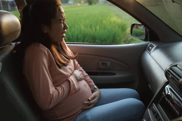 Беременная женщина боли в животе во время поездки на машине — стоковое фото