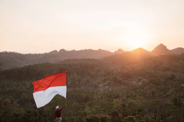 Uomo con bandiera indonesiana dell'indonesia in cima alla montagna — Foto Stock