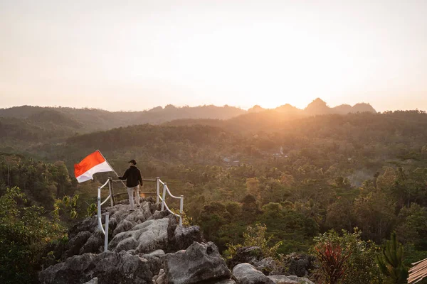 Hombre con bandera indonesia en la cima de la montaña — Foto de Stock