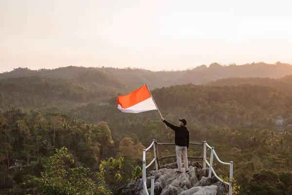 Uomo con bandiera indonesiana dell'indonesia in cima alla montagna — Foto Stock