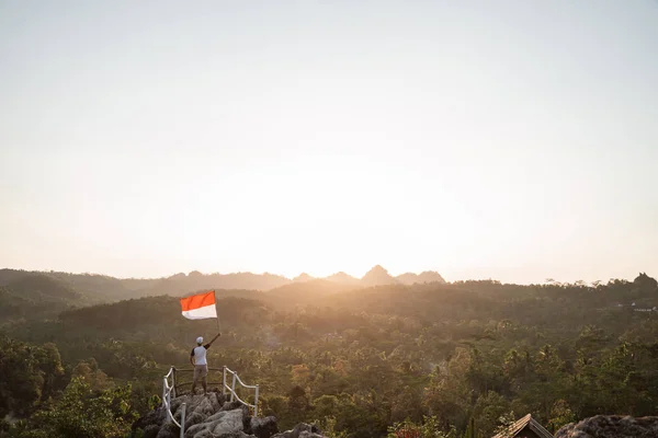 Uomo con bandiera indonesiana dell'indonesia in cima alla montagna — Foto Stock