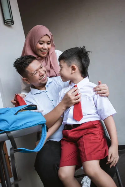 Família feliz com criança vestindo uniforme escolar — Fotografia de Stock