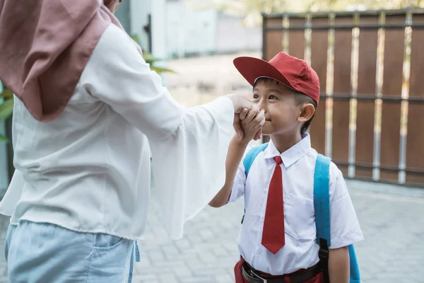 Студент целует родителям руку перед тем как идти в школу — стоковое фото