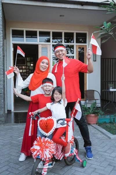 Keluarga mendekorasi sepeda dengan bendera dan busur untuk hari kemerdekaan indonesia — Stok Foto