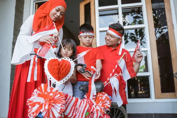 Keluarga mendekorasi sepeda dengan bendera dan busur untuk hari kemerdekaan indonesia — Stok Foto