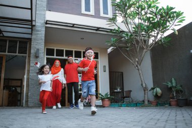endonezya bağımsızlık gününü kutlayan aile birlikte bayrak taşıyor
