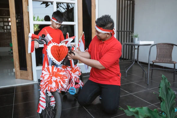 Ayah mendekorasi sepeda dengan bendera indonesia dengan anaknya — Stok Foto