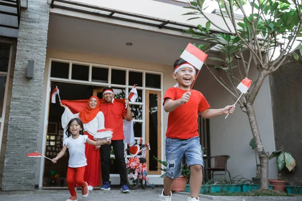 Rodzina obchodzi indonezyjski Dzień Niepodległości razem przewożących flagę — Zdjęcie stockowe