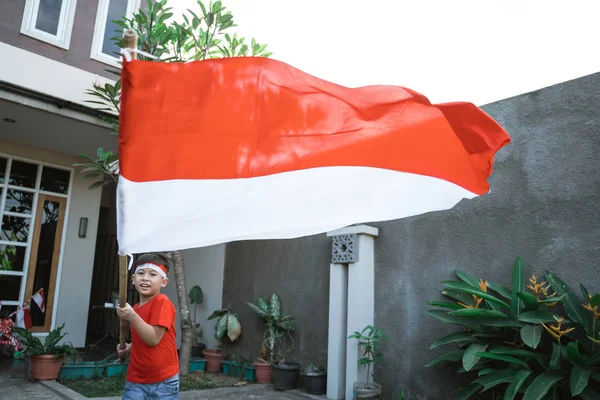 Anak angkat bendera indonesia dan berjalan di sekitar — Stok Foto