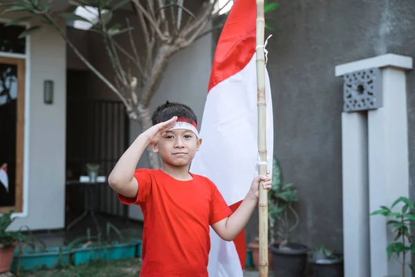 Anak asia memberi hormat sambil memegang bendera indonesia — Stok Foto