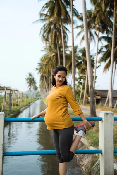 Kobieta w ciąży rozciągać nogę podczas ćwiczeń na zewnątrz — Zdjęcie stockowe