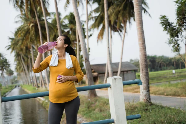 Kobieta w ciąży po treningu picia butelkę wody — Zdjęcie stockowe