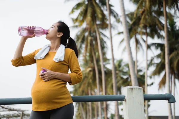 Zwangere vrouw na de training drinken van een fles water — Stockfoto