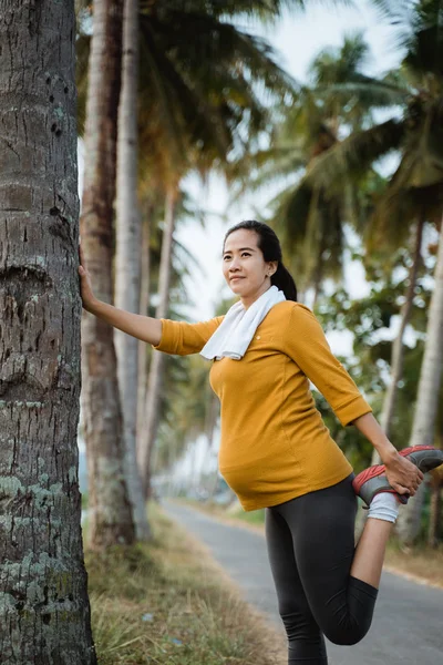 Pregnant woman stretch her leg during exercising outdoor — Stock Photo, Image