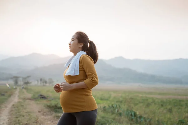 Беременная женщина бегает трусцой на природе — стоковое фото