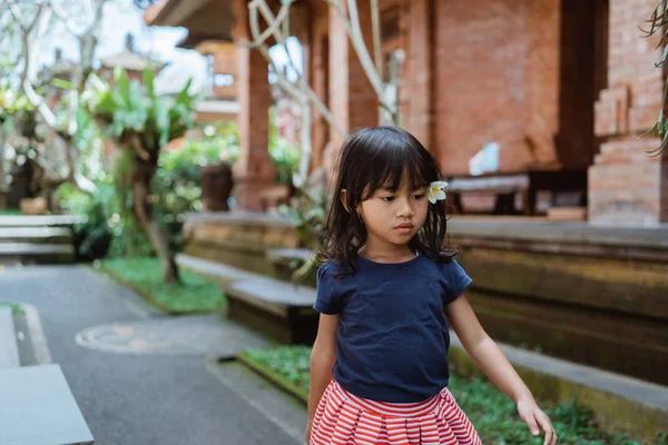 家の外を歩く耳に花を着た小さな女の子 — ストック写真