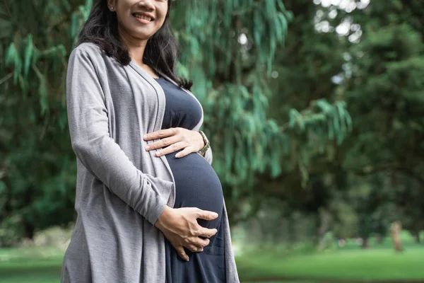 Close up de grávida asiático jovem mulher de pé no parque — Fotografia de Stock