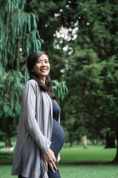 Pregnant asian young woman standing in the park — Stock Photo, Image