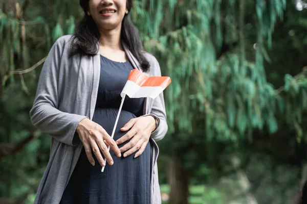 Primo piano di una donna incinta in piedi con una bandiera indonesiana — Foto Stock