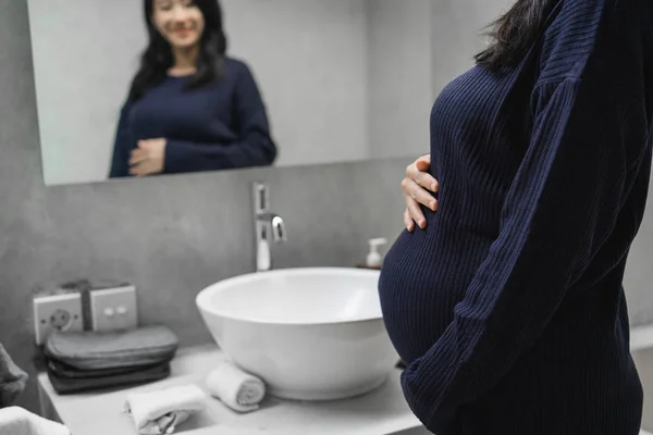 Asiatiska unga mödrar se en spegel i Bad rums — Stockfoto