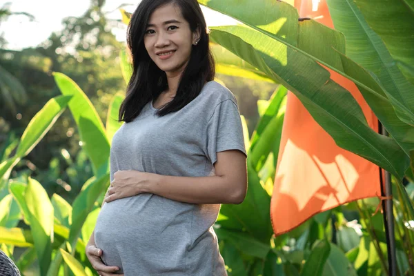 Беременная молодая мать, стоящая с руками — стоковое фото